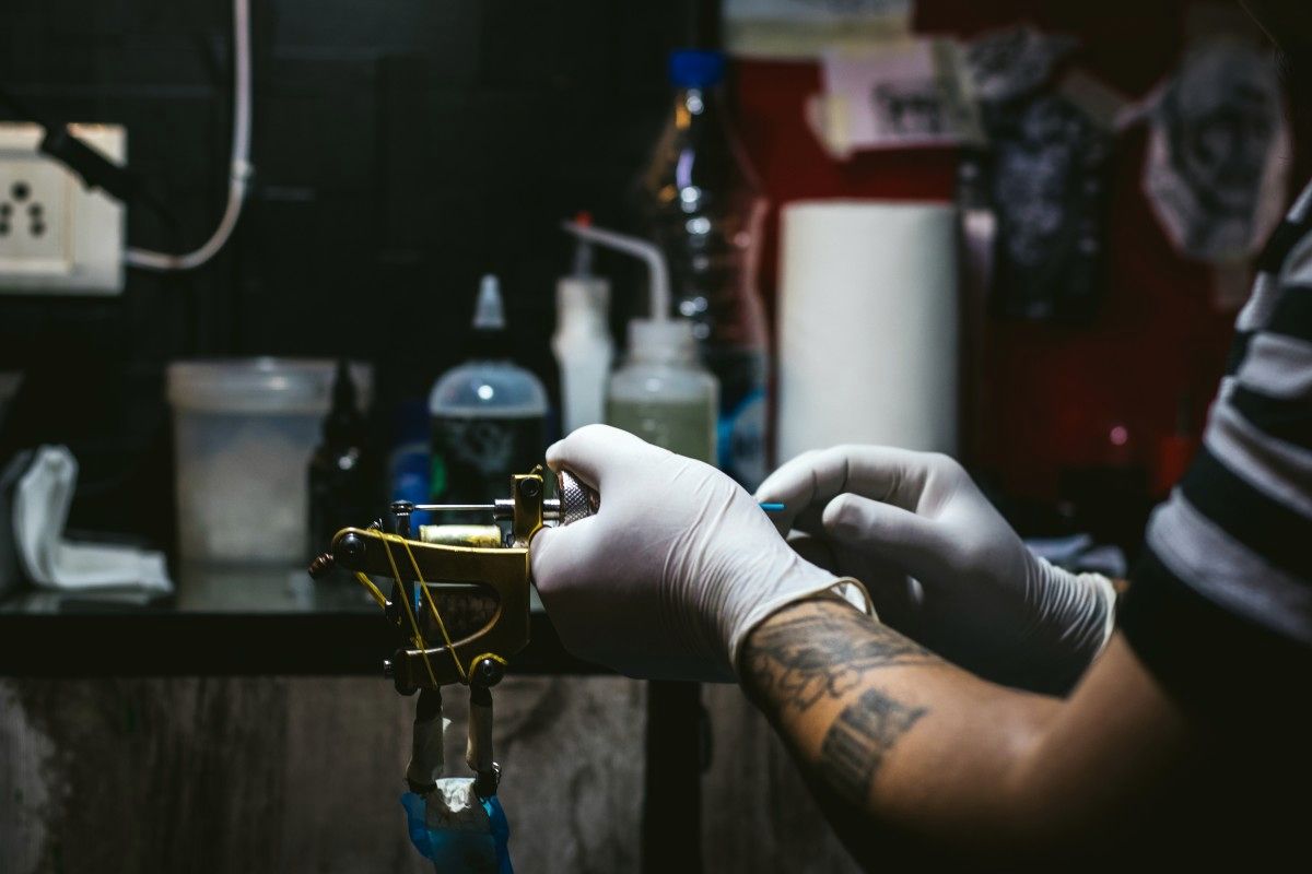 Artist in nitrile gloves preparing a coil machine at a clean station